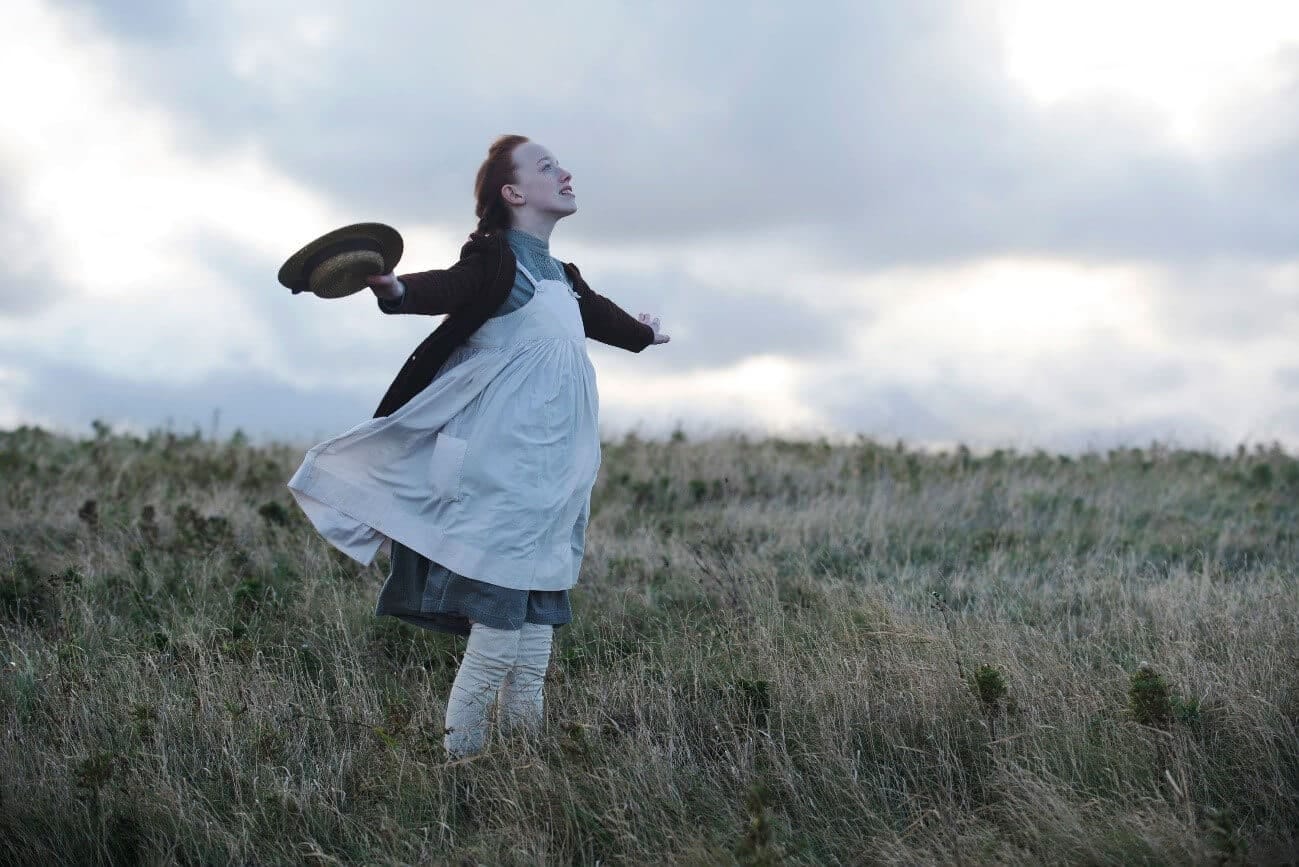 Imagem da Anne com um braço erguido em frente a Fazenda de Green Gables.